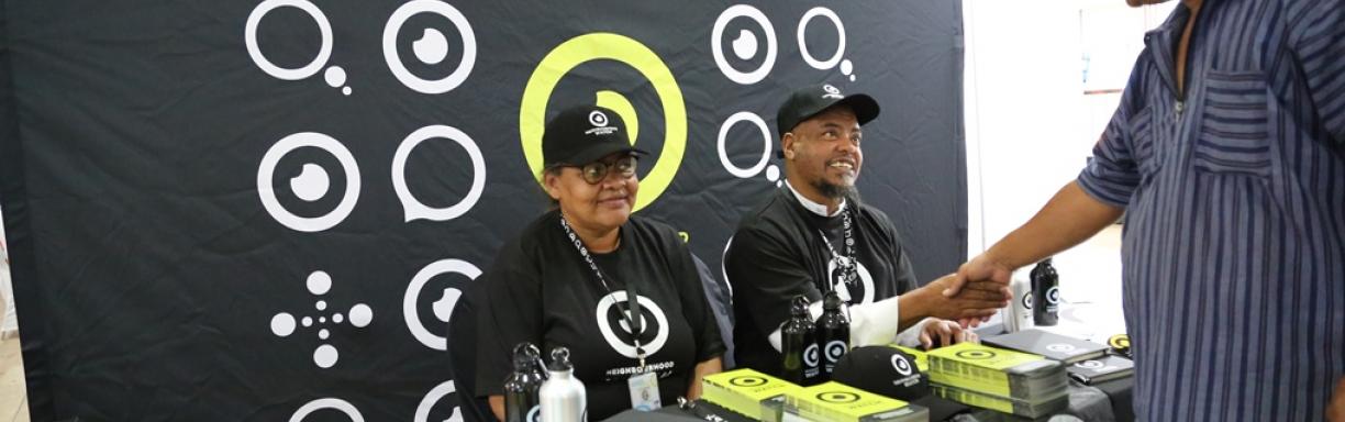 Members of a Neighbourhood Watch sit behind a desk at a campaign