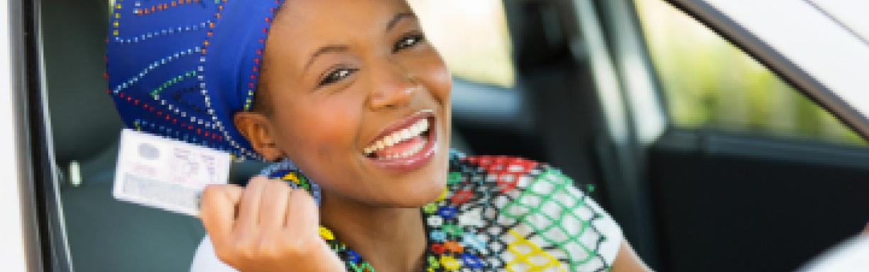 African lady in her car with her driving licence in her hand