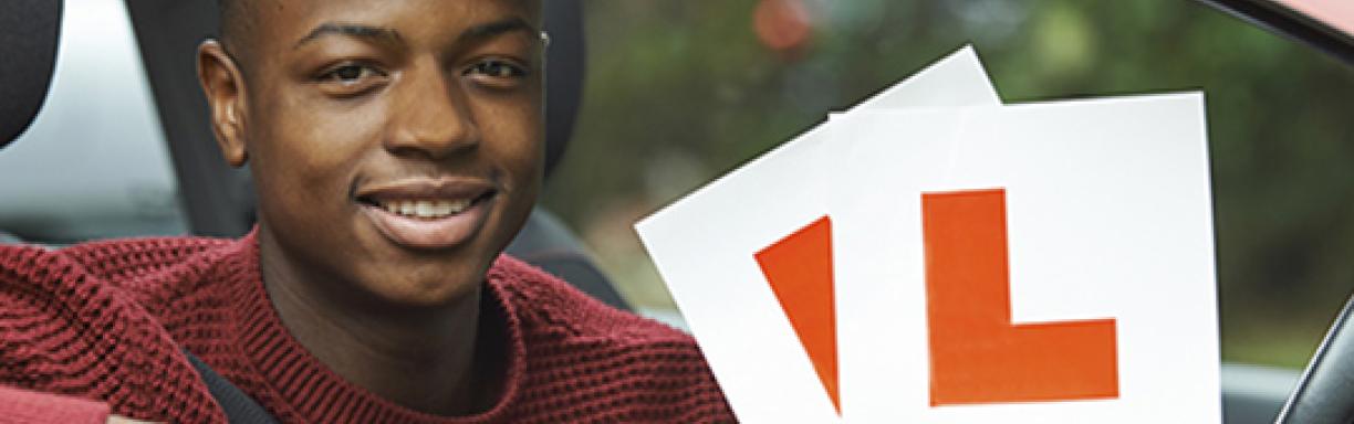 Young man holding the L signs of the car