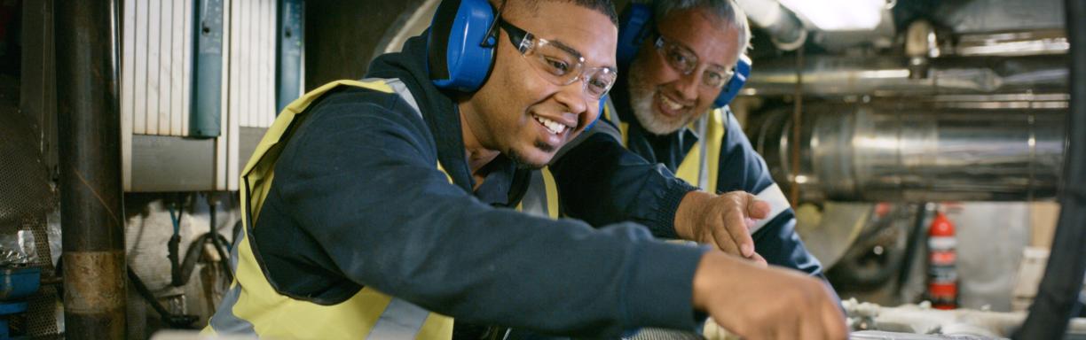 A close up of two men working on a car in a car workshop