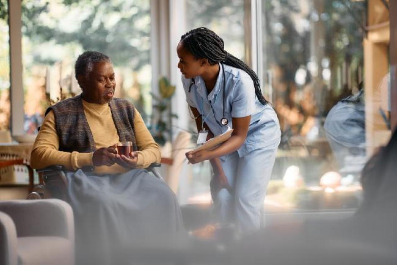 young nurse communicating with senior man in nursing home.