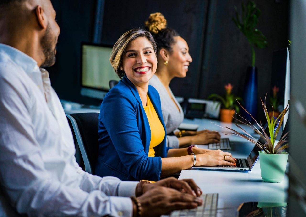 people-smiling-sitting-in-front-on-their-laptops