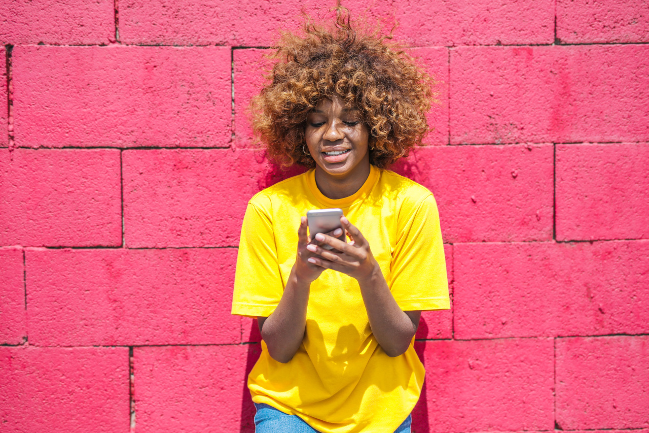 Young lady with a phone in her hand standing against a wall