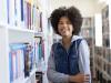 portrait_of_cheerful_teenage_girl_standing_by_bookshelf